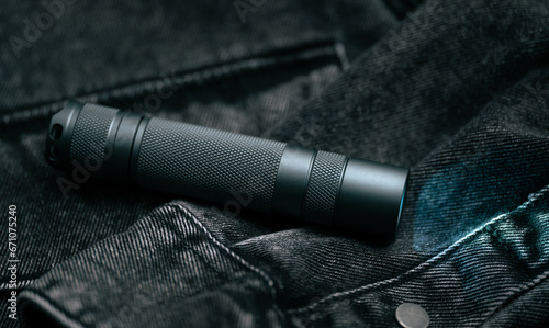 Pocket flashlight for Everyday Carry (EDC) on a dark background. Ray of light.	 photo