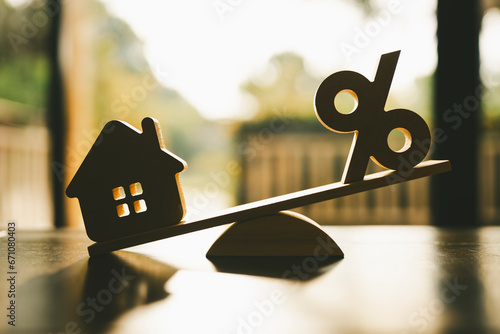 Wooden house model, Percentage symbol on wooden balance with sunlight, Concepts of interest, a symbol for buying a new house, property insurance and security, affordable housing concepts.