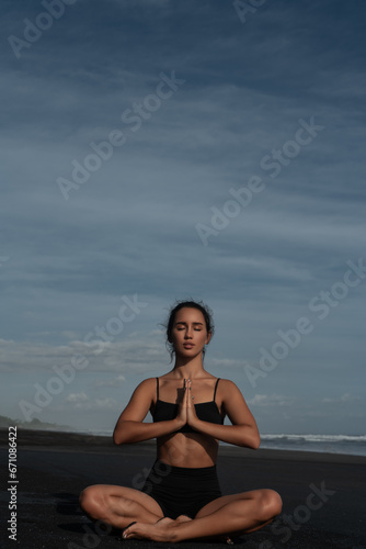 Beautiful girl doing yoga on a black beach near the ocean © ivancheremisin