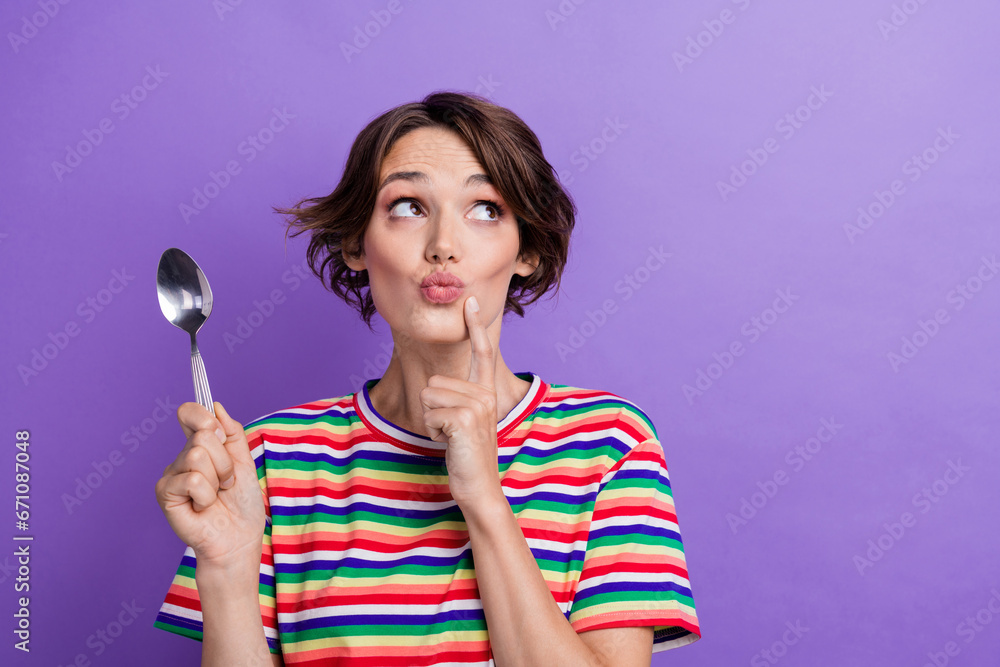 Photo of cute mined girl wear trendy striped clothes hand hold spoon face chin choose meal empty space isolated on purple color background Photo of cute mined girl wear trendy striped clothes hand hold spoon face chin choose meal empty space isolated on purple color background