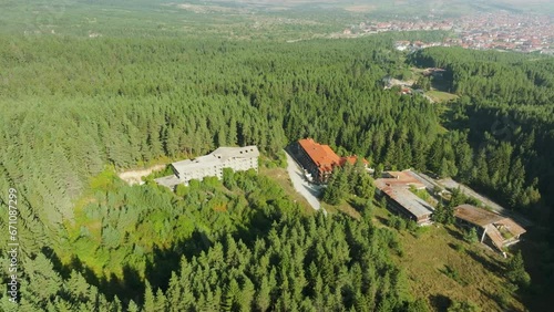 Abandoned hotel construction in the middle of the forest. Cleared plot of land is overgrown with young forest. photo