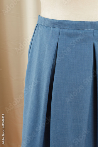 Vintage blue garment. Close-up detail of skirt waist and pleats. Product photograph. Nobody. 