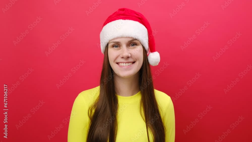 Smiling young woman wearing warm yellow sweater and Santa Claus hat looking at camera cover eye with victory sign, isolated on red background. Happy New Year 2024 celebration Christmas holiday concept Smiling young woman wearing warm yellow sweater and Santa Claus hat looking at camera cover eye with victory sign, isolated on red background. Happy New Year 2024 celebration Christmas holiday concept