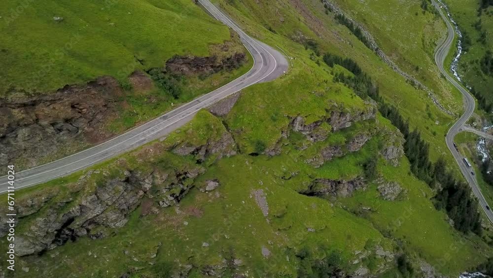 Aerial drone flight above Transfagarasan Road - located on the alpine pastures of Fagaras Mountains. The rocky ridges are covered in green grass. Carpathia, Romania.