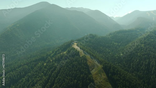 Aerial approach of ski lift station in early summer morning. Beautiful landscape view of surrounding mountains. Pretty nature video, blend of nature and civilization. photo