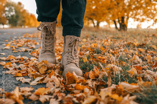 A man walks along an autumn road  boots close-up
