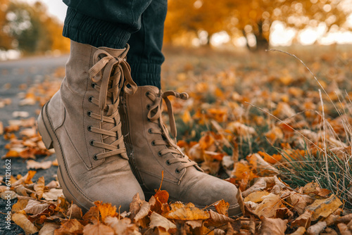 Fototapeta Naklejka Na Ścianę i Meble -  A man walks along an autumn road, boots close-up