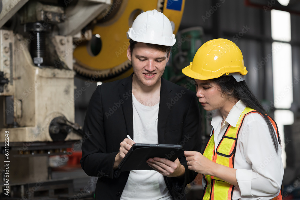 Male and female factory worker working with digital tablet in industry factory. Male and female worker training of work at production line conveyor in factory Male and female factory worker working with digital tablet in industry factory. Male and female worker training of work at production line conveyor in factory