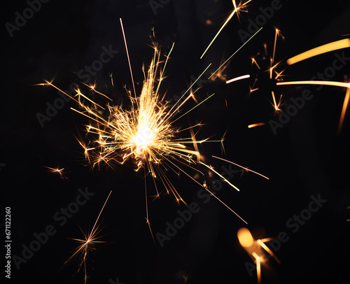Burning sparkler light on black background. New year party background. Overlay of  New Year sparkles.