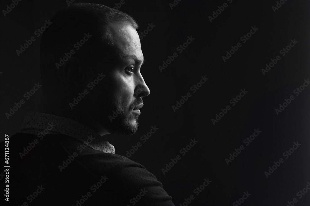 Fabulous at any age. Profile portrait of charismatic 40-year-old man posing over black background. Short haircut. Classic, smart casual style. Close up. Copy-space. Black and white studio shot - obrazy, fototapety, plakaty 