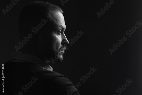 Fabulous at any age. Profile portrait of charismatic 40-year-old man posing over black background. Short haircut. Classic, smart casual style. Close up. Copy-space. Black and white studio shot photo