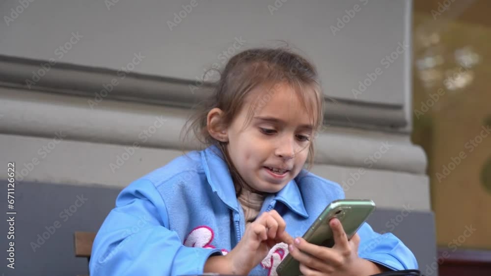The girl using smartphone. playing games or looking information. Child and gadget. The girl using smartphone. playing games or looking information. Child and gadget.