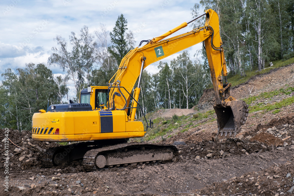 A yellow excavator works in the mountains. Construction of roads and houses in beautiful mountains. A yellow excavator works in the mountains. Construction of roads and houses in beautiful mountains.