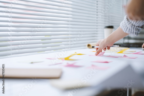 Hands of businesswoman sticking notes on table when working on project roadmap