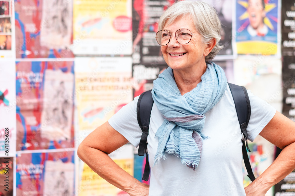 Fototapeta premium Happy carefree senior woman tourist walking in Seville, Spain holding a backpack enjoying vacation trip freedom, healthy lifestyle in retirement