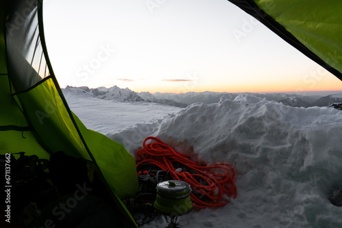 Winterbiwak im Schnee auf einem Berg in den Alpen mit grünem Zelt