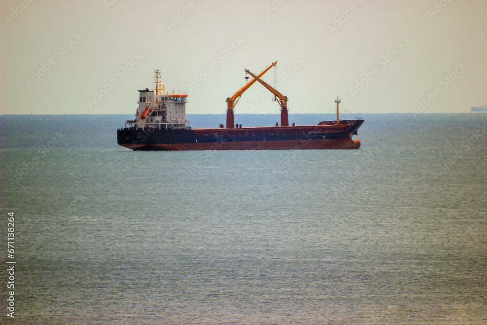 steel ship on the horizon in the Black Sea with crossed cranes	

