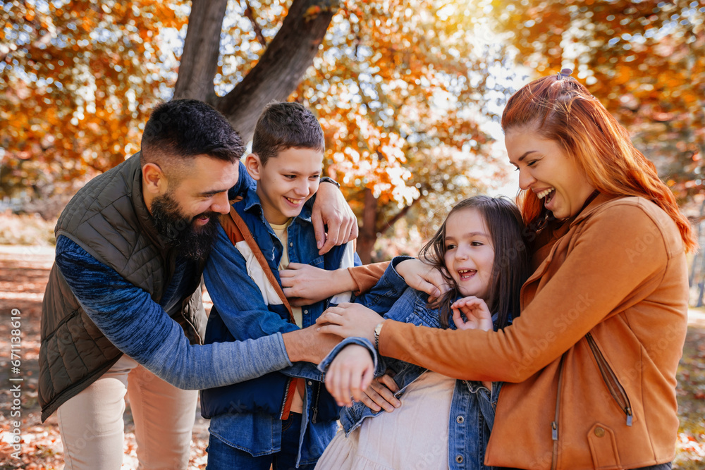 Parents tickle their children. Sunny autumn day in the colorful park Parents tickle their children. Sunny autumn day in the colorful park