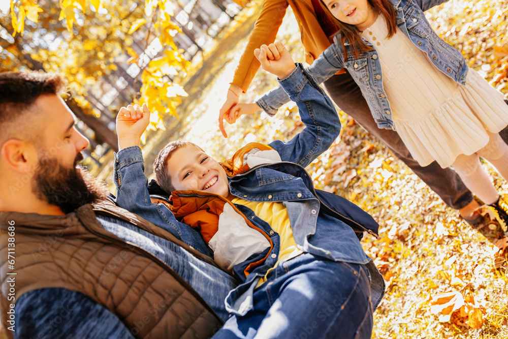 Fototapeta premium Parents tickle their children. Sunny autumn day in the colorful park