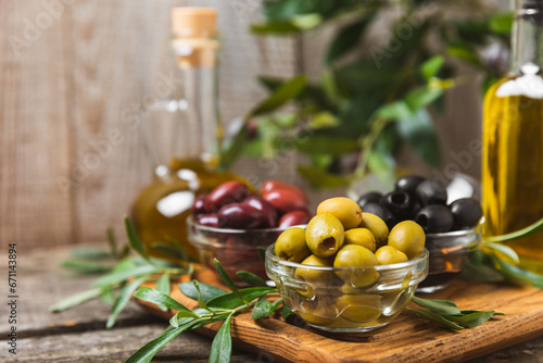 A set of green, red and black olives on background. Various types of olives in bowls and fresh olive leaves. Vegan. Olive fruits. Place for text. Copy space.