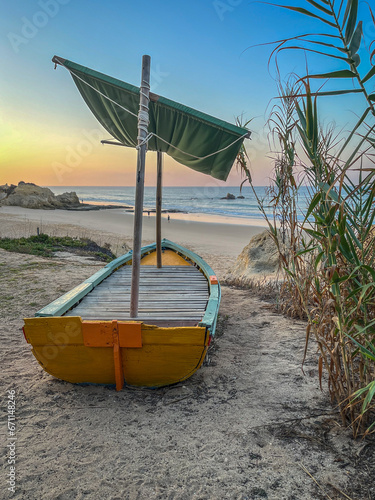 Barque à voile échouée sur le sable face au lever de soleil sur l'océan au Portugal