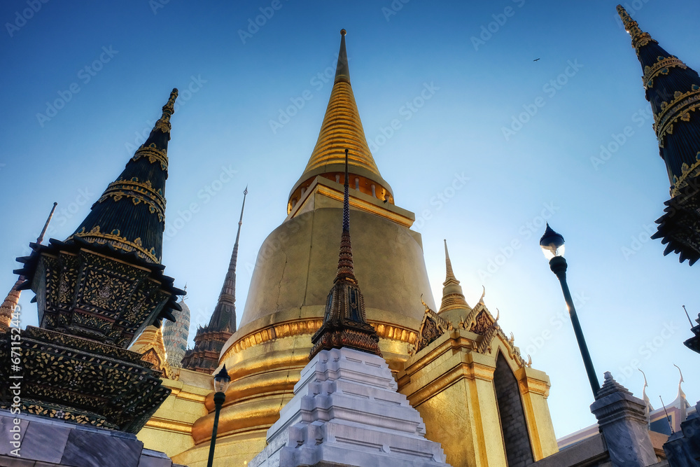 Fototapeta premium Located in Thailand, this temple boasts a huge golden stupa and a few ornate spires of smaller sizes. The details of the structure are intricate. Thai architectural excellence.