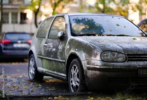 Porzucone srebrne auto pokryte brudem i mchem stojące na osiedlowym parkingu w mieście