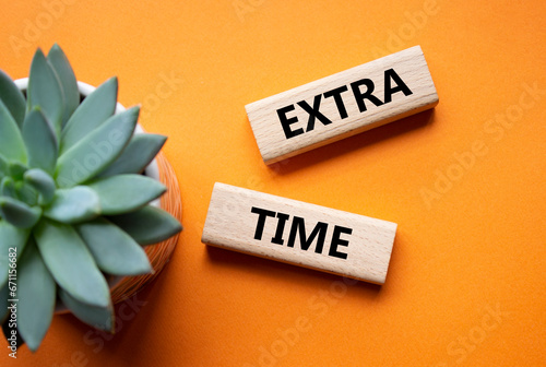 Extra time symbol. Concept word Extra time on wooden blocks. Beautiful orange background with succulent plant. Business and Extra time concept. Copy space