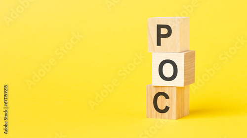 wooden blocks with the text POC - short for Proof of Concept on a bright yellow background