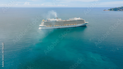 High-angle shot from a drone The largest cruise ship in Asia in front of Patong Beach, Phuket, mountain and sea atmosphere. © Stock.Foto.Touch