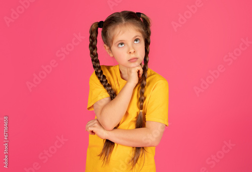 Pensive preteen female child touching her chin, thinking about something