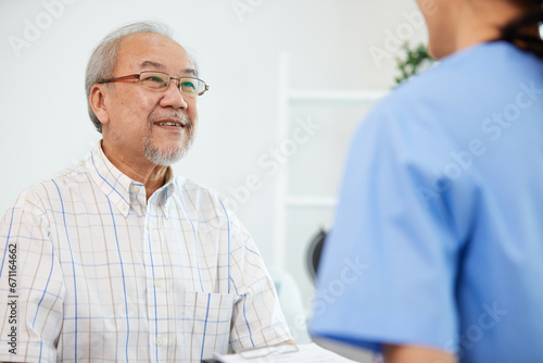 elderly man smiling and talking with caregiver on sofa