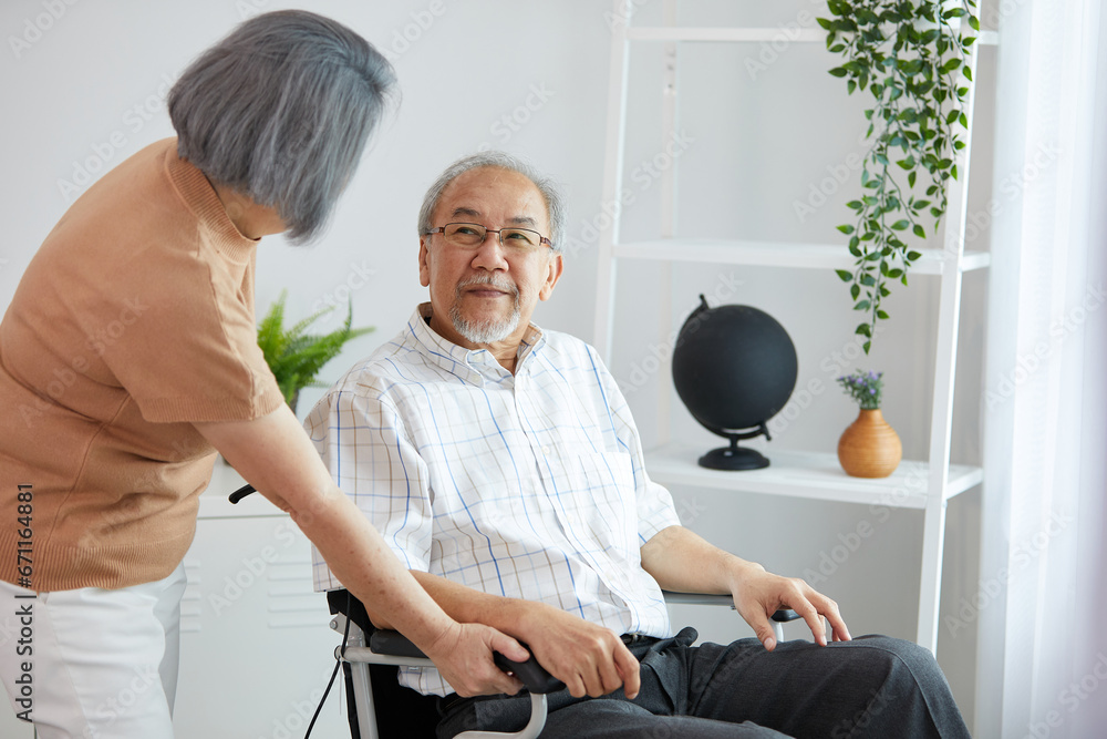 Fototapeta premium elderly man sitting on wheelchair and his wife talking care at home