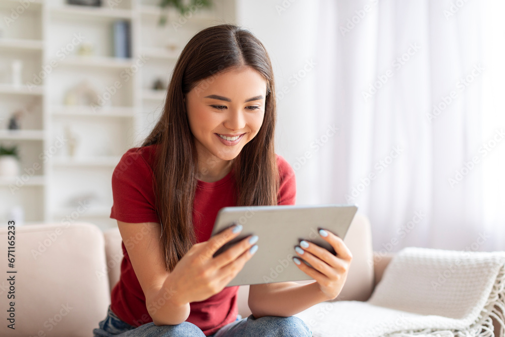 Smiling young asian woman relaxing with digital tablet at home Smiling young asian woman relaxing with digital tablet at home