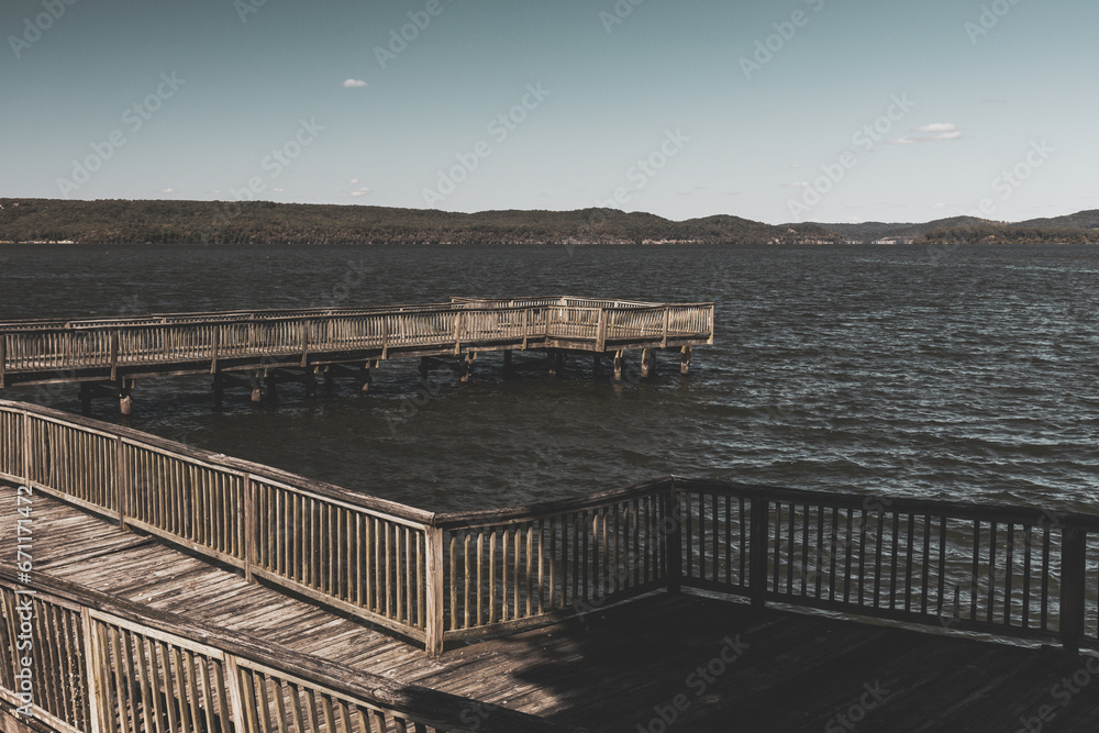 Tranquil landscape of wooden river pier over lake water with blue sky and mountains in background at Lake Guntersville, Alabama