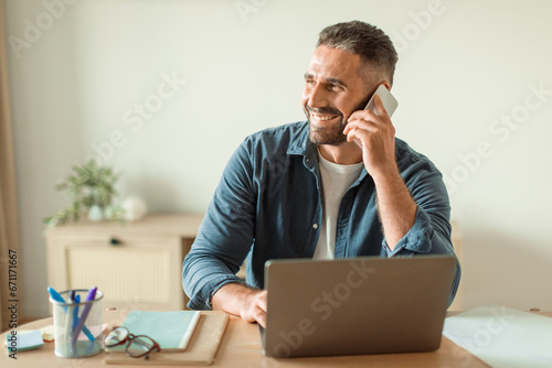 Middle Aged Guy Talking On Phone Sitting At Workplace Desk