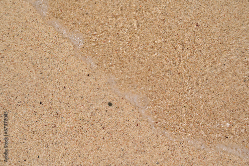 Wet sand on beach, closeup detail from above. Abstract sea background.
