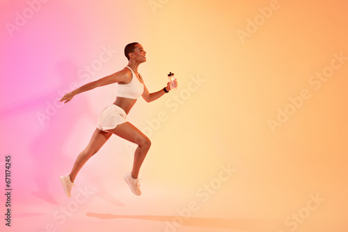 Concentrated young latin lady athlete in sportswear run with bottle of water
