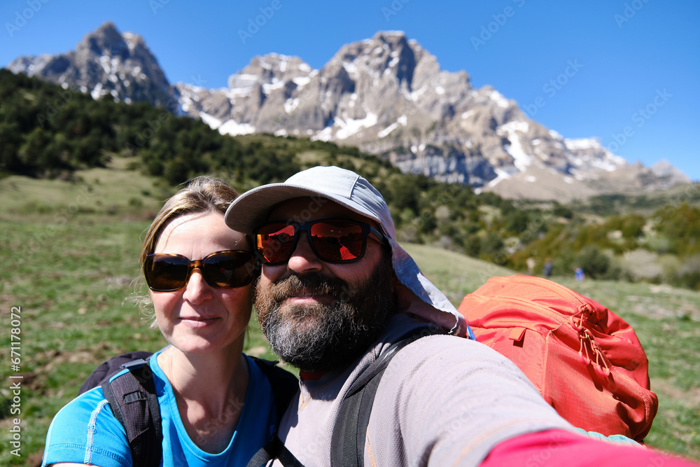 Happy hiking couple in sunglasses standing together in mountainous countryside