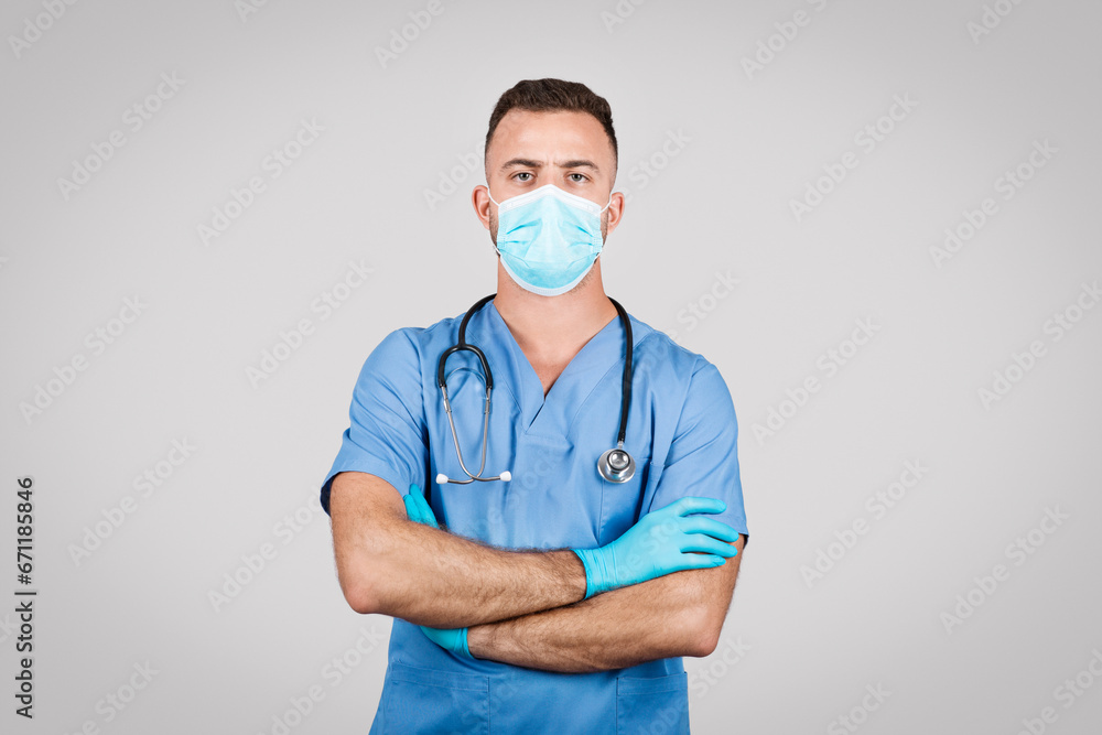 Doctor man in protective mask posing with crossed arms on grey background Doctor man in protective mask posing with crossed arms on grey background