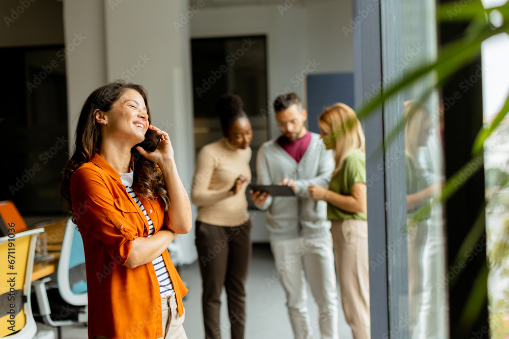 Young business woman with mobile phone in front of her team at the office Young business woman with mobile phone in front of her team at the office