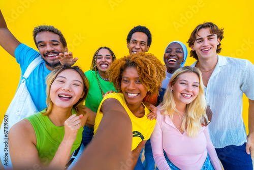 Young multi-ethnic people taking a selfie in a yellow background