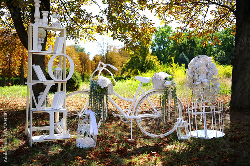 Wedding decoration in nature. Vintage bicycle decorated with flowers. Shelf with books. And the inscription (love) in capital letters.