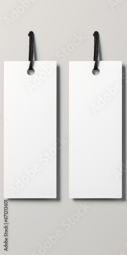 Two blank white paper tags hanging on a wall. Can be used for labeling or organizing purposes.