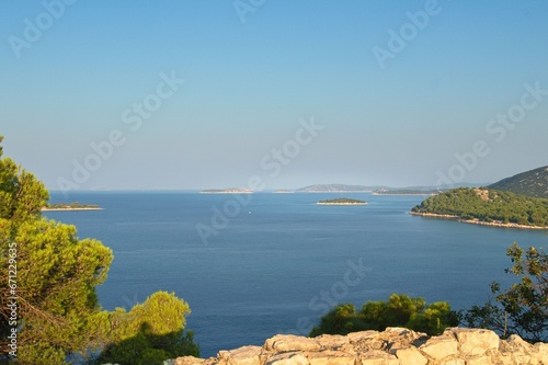 View from view point to Adriatic sea from town Tribunj during sunrise with cute small islands in the background and stones and vegetation in foreground photo