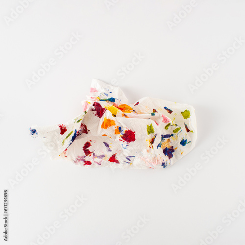 Crumpled paper splattered with vibrant multicolor paint on white background. Minimal composition. Artistic colorful idea.