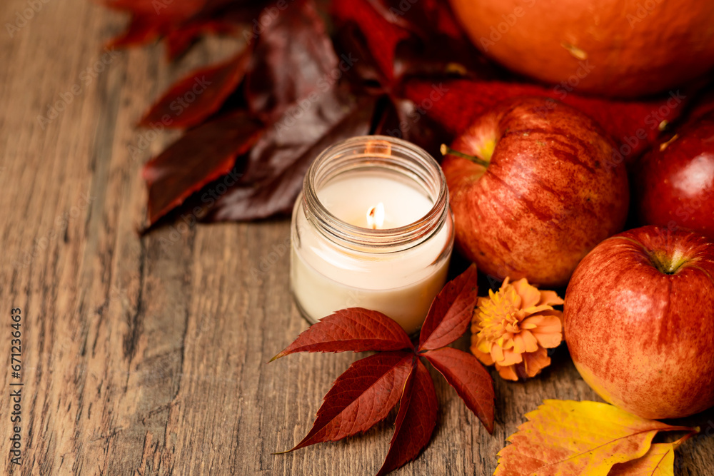 Burning candle on the table next to apples and grape leaves. Autumn Composition Burning candle on the table next to apples and grape leaves. Autumn Composition