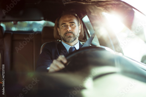 Focused businessman drives his car in the morning light photo
