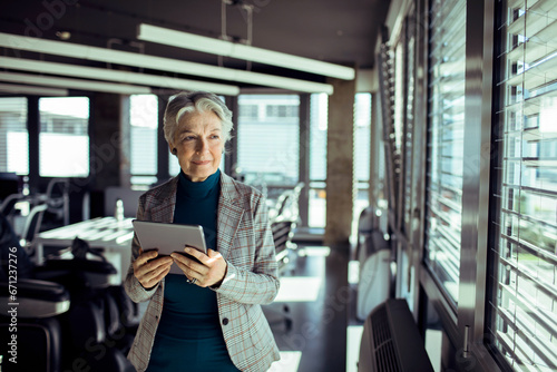 Senior businesswoman confidently using a tablet in a modern office photo