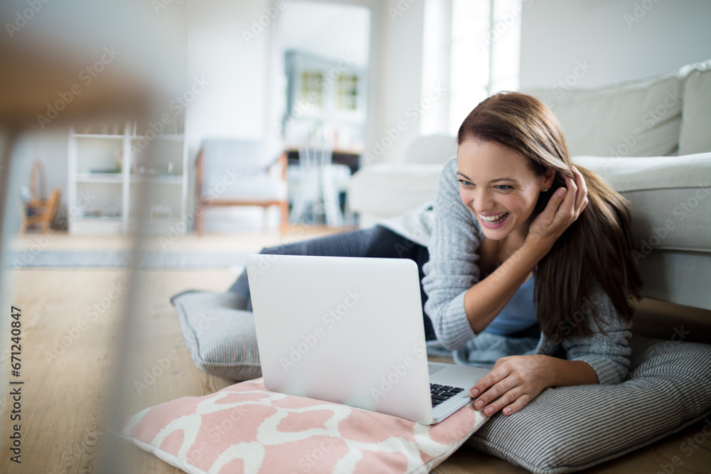 Happy woman working on her laptop from the comfort of her living room Happy woman working on her laptop from the comfort of her living room